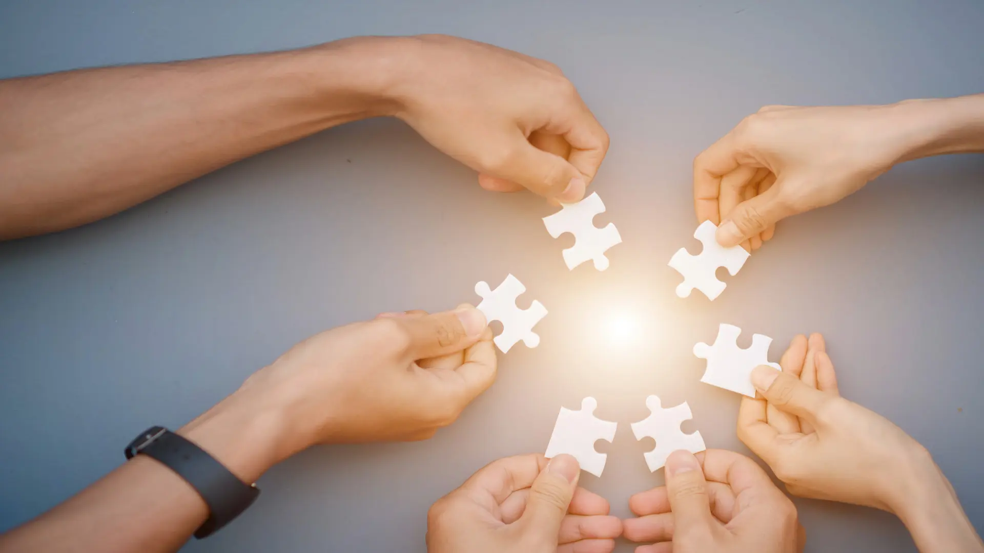 Four hands each holding glowing puzzle pieces, symbolizing healing, connection, and stress recovery – Chronic Health Wisdom