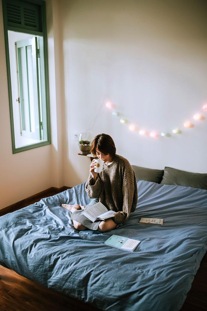 Woman sitting on bed and reading a book.