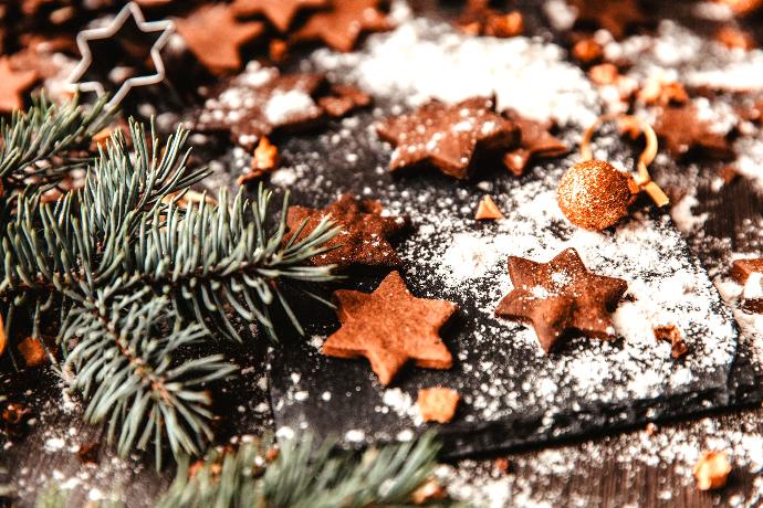 Picture of flower one little holiday cookies next to a pine branch.