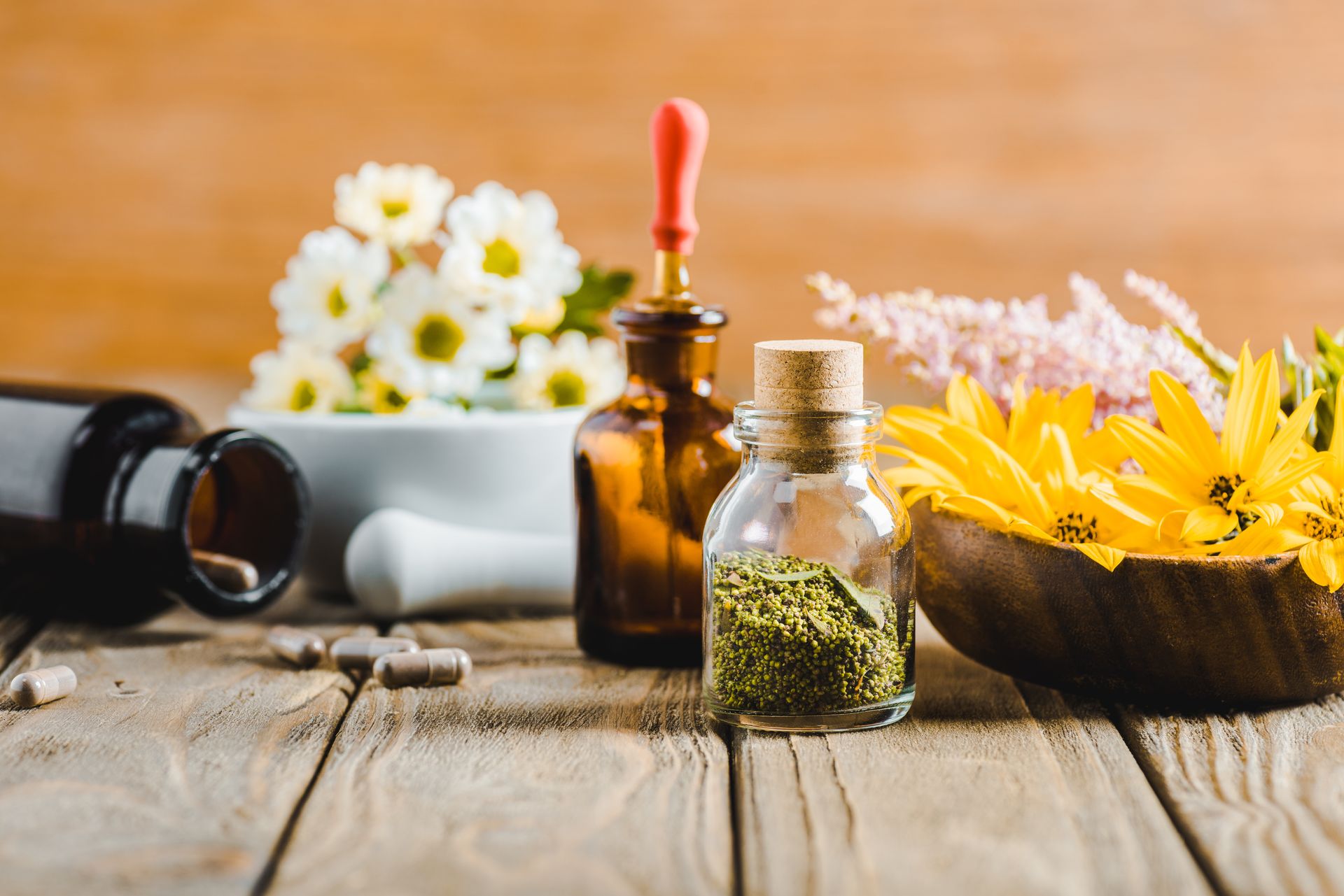 Spices in bottles, bowls of flowers on a wooden table.Alternative Health Options.